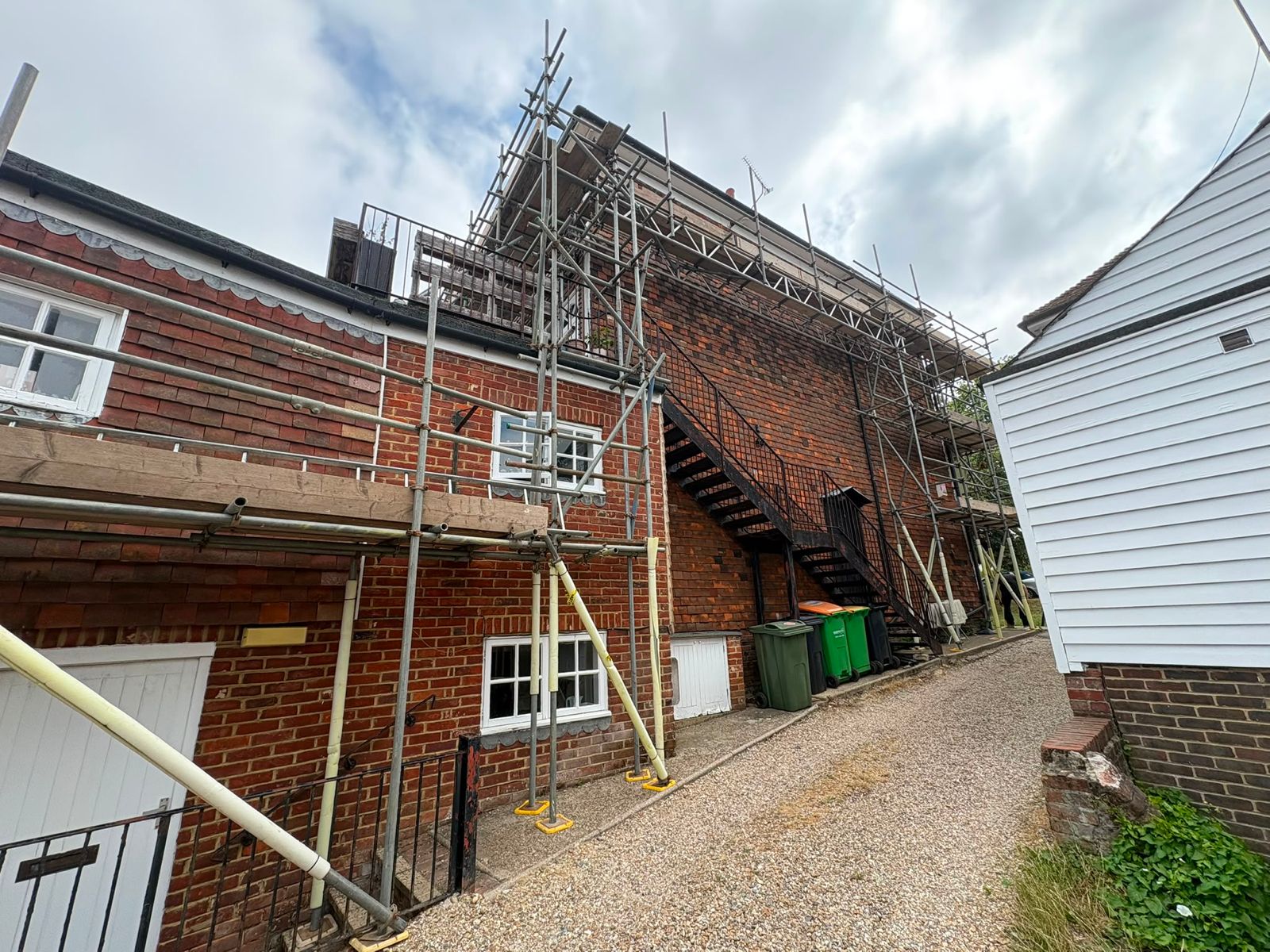 Roofing scaffolding with stair access to the side of a red brick house in Kent