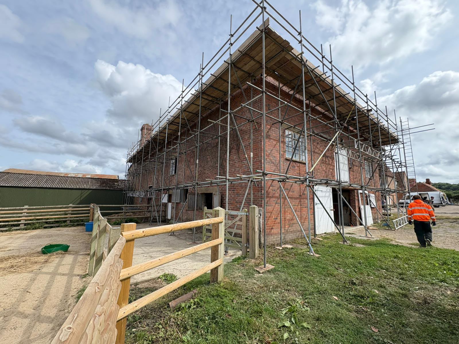 Renovation scaffolding around a large brick farm building under refurbishment